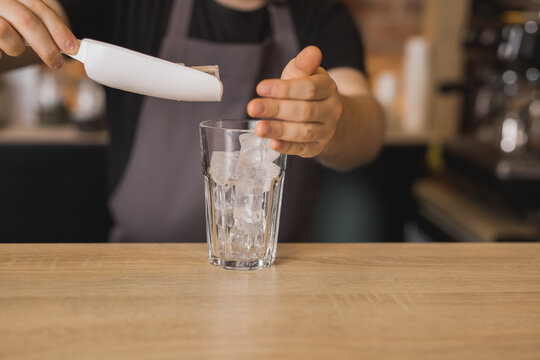 Barista preparing drink with ice cubes