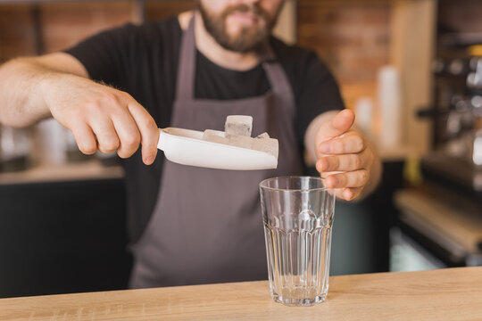 Barista preparing drink with ice cubes