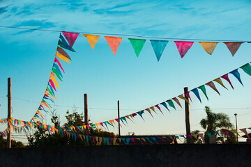 Low angle view of a bunch of colored pennants hanging like garlands for a party outdoors.