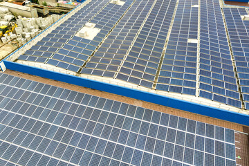 Fototapeta premium Aerial view of solar power plant with blue photovoltaic panels mounted of industrial building roof.