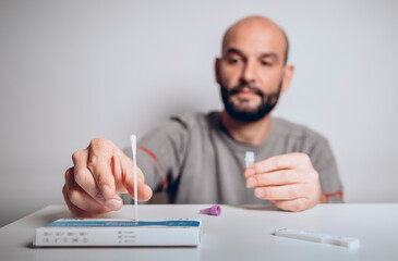 man taking nasal swab from covid antigen test in study shot on white background