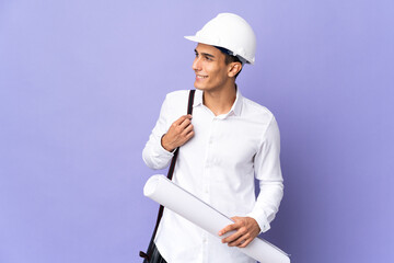 Young architect man isolated on background looking to the side and smiling