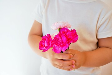 赤ちゃんが握る赤とピンクのカーネーションの花のブーケ