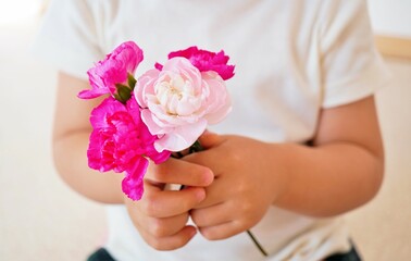 幼児が持つ赤とピンクのカーネーションの小さい花束
