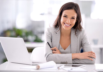 She's made it. Shot of an attractive businesswoman sitting at her desk in an office.