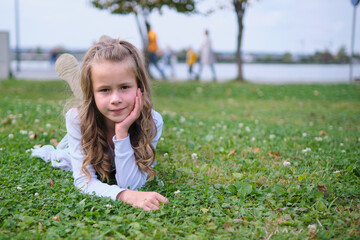 Portrait of pretty child girl outdoors lying down on grass lawn