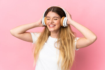 Young blonde woman isolated on blue background listening music