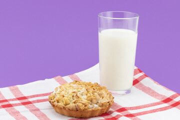 Full glass of milk with lemon shortbread on red-white striped kitchen towel against purple background. Cookies with milk for the night. Food bedtime concept background with copy space