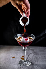 the bartender pours coffee into a cocktail with ice cream with his hand