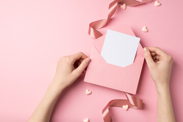First person top view photo of valentine's day decor young woman's hands holding open pink envelope...