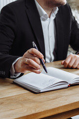 man's hand with a pen over a diary
man writes in his diary