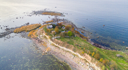 Aerial sunset colored view to the thin cape badly suffering by coastal erosion and with the abandoned historic guard station buildings, nearly to collapse to the sea. Concept of coastal erosion