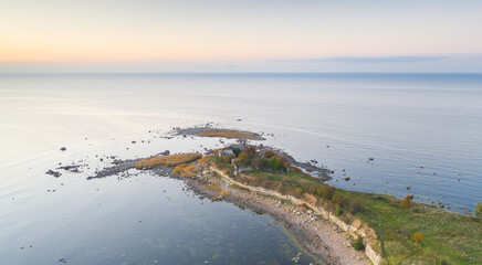 Aerial sunset colored view to the thin cape badly suffering by coastal erosion and with the...