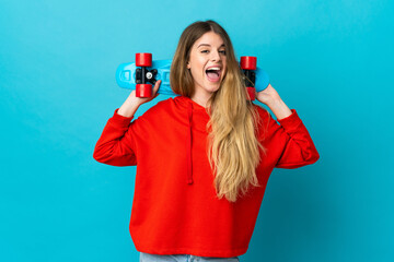Young blonde woman isolated on blue background with a skate