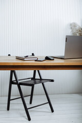 a desk with a chair, on the desk there is a laptop, an organizer, a pen and a computer mouse