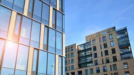 View of an modern apartment building standing next to a new modern office building with a glass facade. - obrazy, fototapety, plakaty