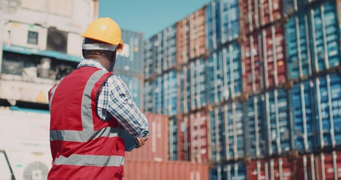ndustrial Engineer with Tablet and Black African American Male Supervisor in Hard Hats and Safety Vests Stand in Container Terminal. Colleagues Talk About Logistics Operations