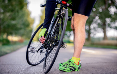 Naklejka premium Cyclist on the road checks the transmission. Sport and recreation concept