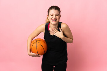 Young blonde woman playing basketball isolated on pink background smiling a lot