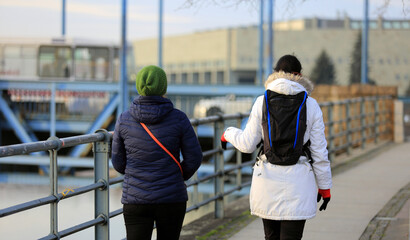 Dwie kobiety z plecakami idą mostem Grunwaldzkim we Wrocławiu. - obrazy, fototapety, plakaty