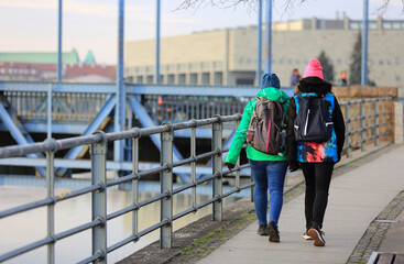 Dwie kobiety z plecakami idą mostem Grunwaldzkim we Wrocławiu.