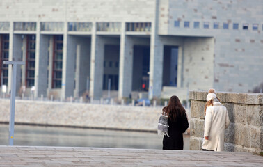 Współczesny budynek urzyteczności publicznej, dwie kobiety na spacerze. - obrazy, fototapety, plakaty