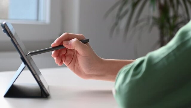 Close up 4K 60fps video of child tapping tablet doing homework at online course