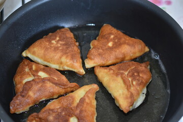 Cooking meat pies in a pan in the kitchen