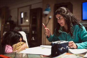 A mother scolds her daughter while doing homework at home