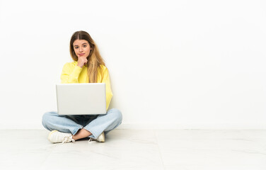 Young woman with a laptop sitting on the floor thinking an idea while looking up