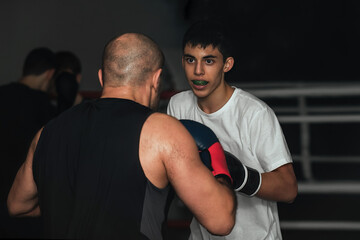 Two sportsmen boxers of different ages train in the classroom in the gym. They are practicing the...