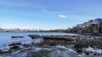 Panoramic view of waterfront buildings and downtown skyline against blue sky from the coast at low tide
