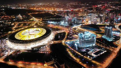 Aerial drone night shot of iconic illuminated London Stadium facilities in Queen Elizabeth Park,...