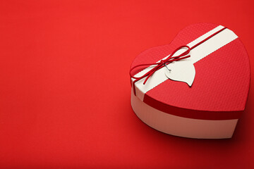 Composition for Valentine's Day February 14. Red background and heart shaped box of chocolates. Postcard. Flat lay.