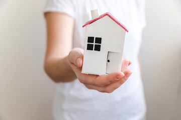 Woman hand holding toy model house isolated on white background. Real estate mortgage property insurance dream home concept. Offer of purchase rental house, family life, business real estate