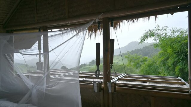 Wooden hut resort with mosquito net on the bed among the nature in rainy day