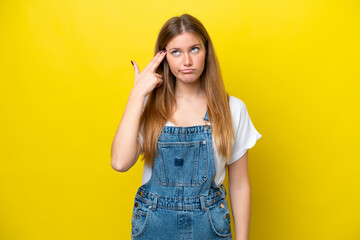 Young caucasian woman isolated on yellow background with problems making suicide gesture
