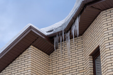 Icicles onroof of private house resulting from improper construction of roof. Metal Downpipe...