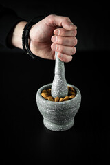 Mortar and pestle filled with fresh almonds on a dark black background. Diet concept.