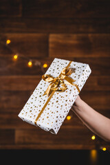 Hand holding a present or Christmass gift on the wooden background.
