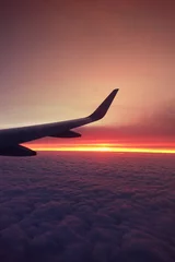 Fototapete Aubergine Sonnenuntergang am bewölkten Himmel, wie von einer Fensterebene über flauschigen Wolken aus gesehen