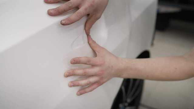 A white film is glued to a car, car detailing. Car foil. Car paint protection, protect coating installation.