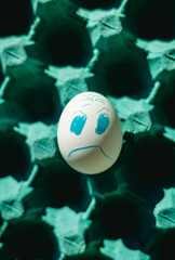 Angry face chicken white egg on a tray. Close-up photo. Concept of emotions and life difficulties....