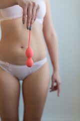 a girl with a toned figure holds a vibrator by the tail to train the pelvic floor muscles. the...