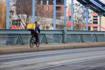 Kurier na rowerze, dostarcza jedzenie na moście Grunwaldzkim we Wrocławiu.	 - obrazy, fototapety, plakaty