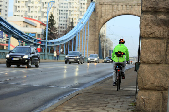 Mężczyzna na rowerze z torebką jedzie mostem Grunwaldzkim we Wrocławiu.	