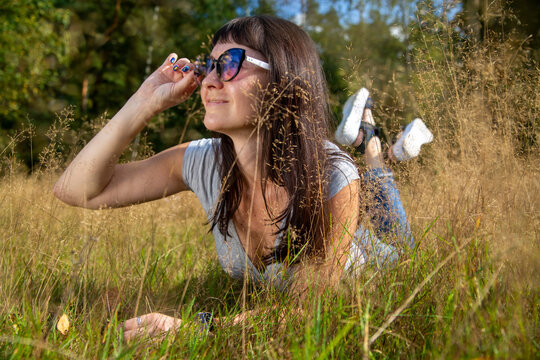 happy carefee young woman lies in grass in sunshining