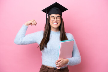 Young student Brazilian woman wearing graduated hat isolated on pink background doing strong gesture