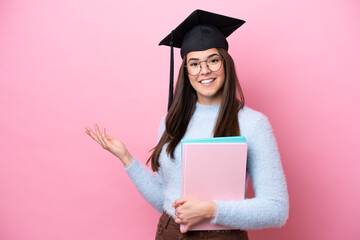 Young student Brazilian woman wearing graduated hat isolated on pink background extending hands to...