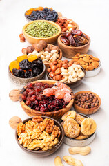 Dried fruits nuts in bowls set. Dry apricots, figs, raisins, walnuts, almonds and other. Healthy nutritious snacks. White table background, top view, copy space